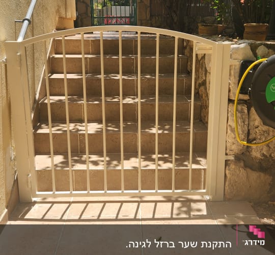 שער מתכת לבן עם סורגים מול מדרגות אבן